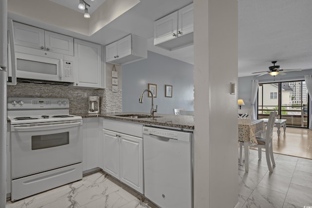 kitchen featuring white appliances, a sink, light marble finish floors, ceiling fan, and dark stone countertops