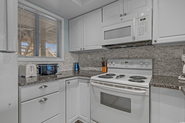 kitchen featuring white appliances, white cabinetry, decorative backsplash, and dark stone counters