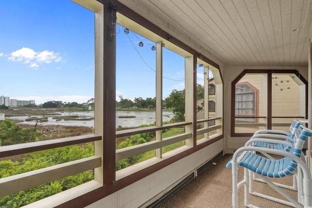 sunroom / solarium featuring a water view, carpet flooring, plenty of natural light, and wood ceiling