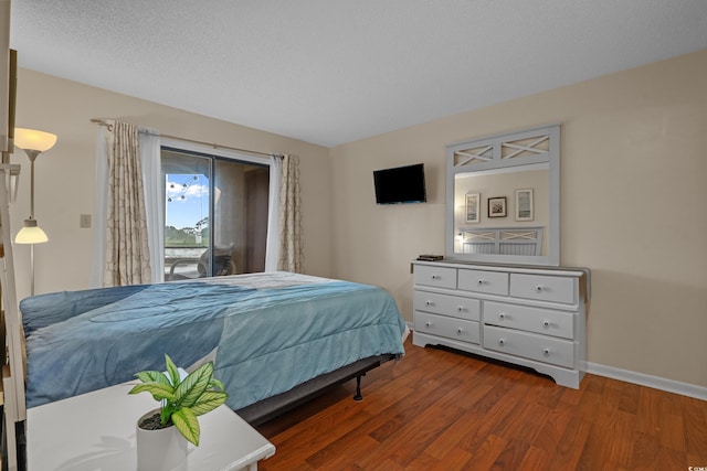 bedroom with wood finished floors, access to outside, and baseboards