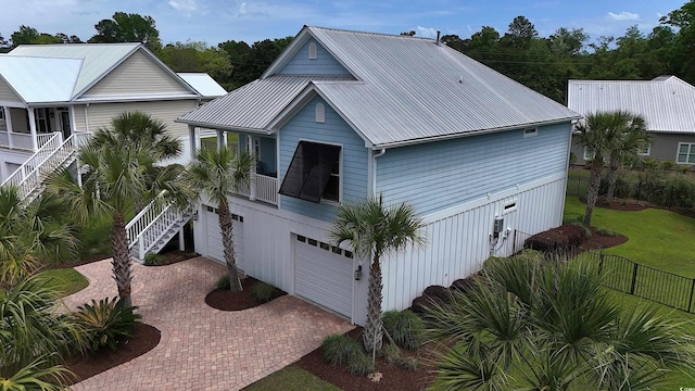 view of front of house featuring an attached garage, decorative driveway, stairway, and metal roof