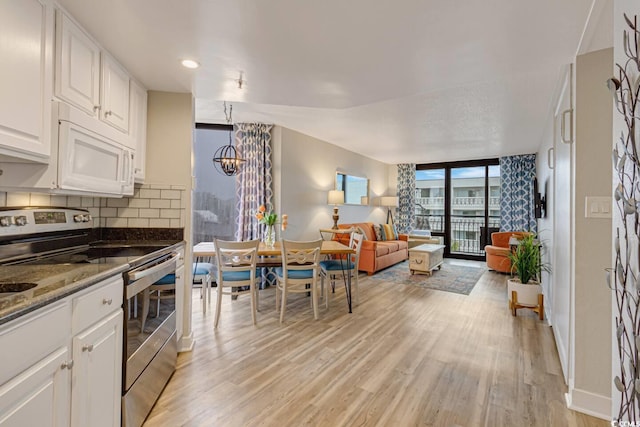 kitchen with stainless steel range with electric stovetop, white microwave, light wood-style floors, a chandelier, and decorative backsplash