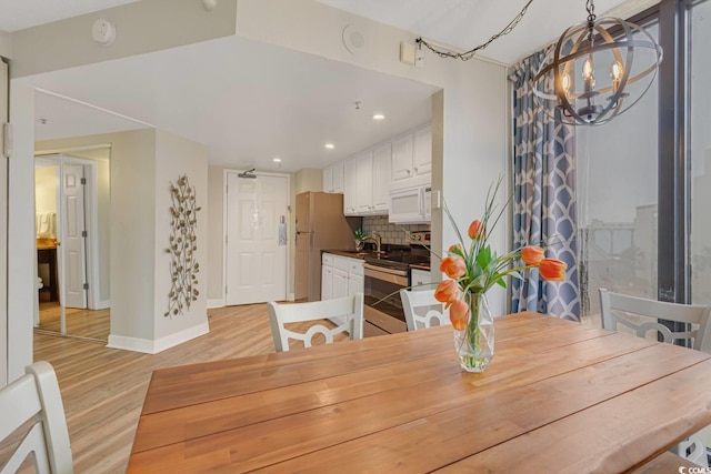 dining room with a chandelier, baseboards, light wood-type flooring, and recessed lighting
