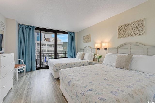 bedroom with access to outside, light wood finished floors, and floor to ceiling windows