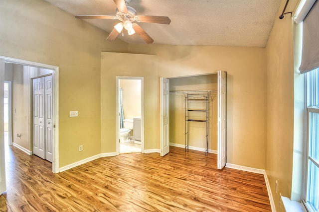 unfurnished bedroom featuring light wood-style floors, a textured ceiling, connected bathroom, a closet, and a ceiling fan