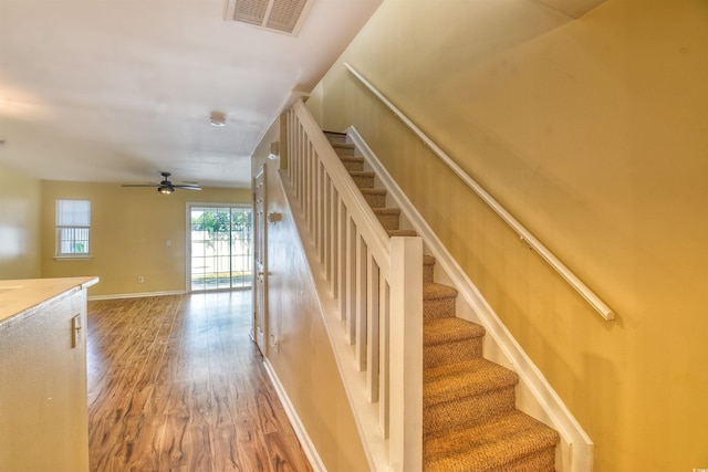 staircase with wood finished floors, baseboards, and ceiling fan