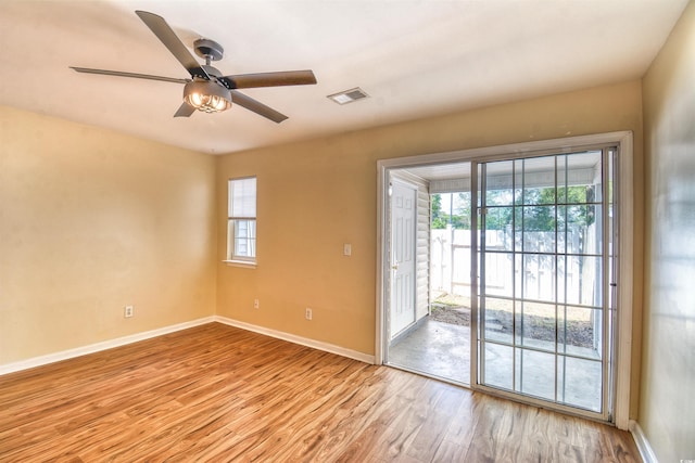 spare room with wood finished floors, baseboards, plenty of natural light, and a ceiling fan