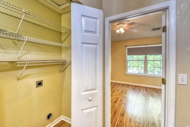 laundry room with electric dryer hookup, wood finished floors, baseboards, and ceiling fan