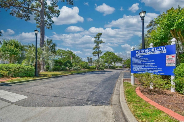 view of asphalt road with street lights and curbs