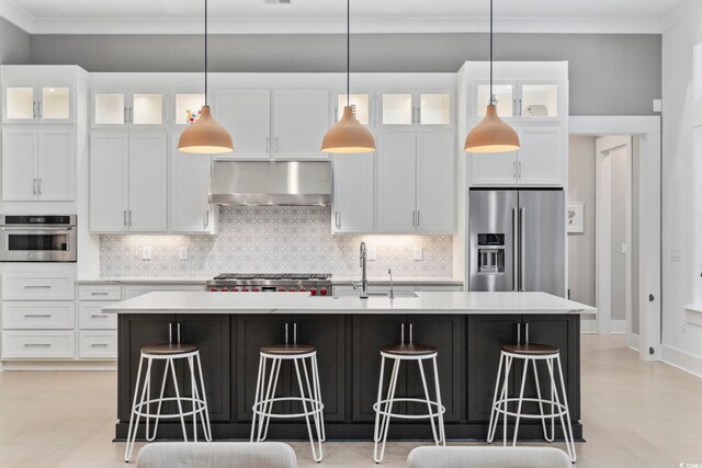 341 Brickwell Ln, Pawleys Island, SC 29585 - kitchen featuring under cabinet range hood, appliances with stainless steel finishes, a kitchen island with sink, a kitchen breakfast bar, and ornamental molding