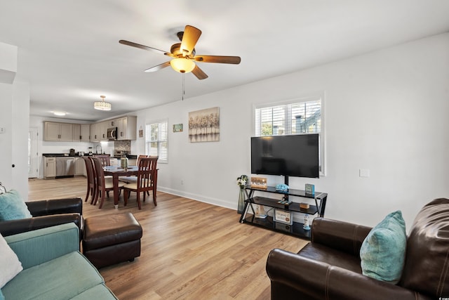 living room with ceiling fan, light wood finished floors, and baseboards