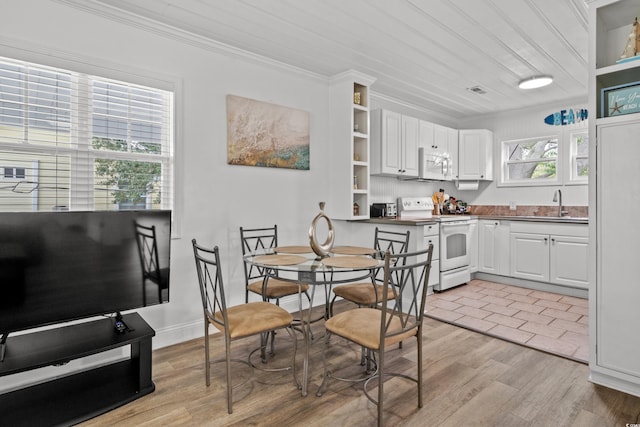 dining room with ornamental molding, light wood-type flooring, and baseboards