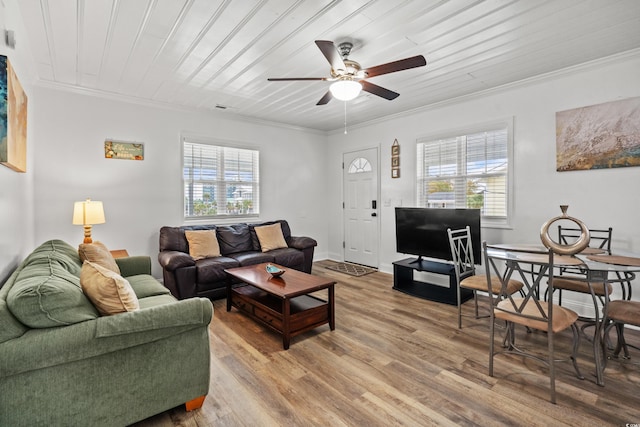 living area with crown molding, a ceiling fan, healthy amount of natural light, light wood-style floors, and wood ceiling