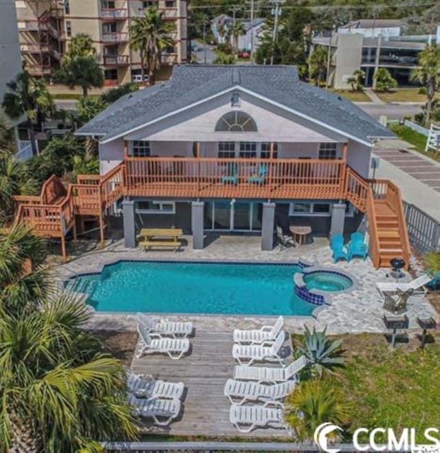 view of swimming pool featuring stairway, a deck, a pool with connected hot tub, and a patio