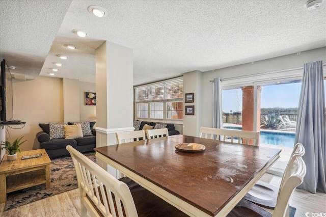 dining area with a textured ceiling, light wood finished floors, and recessed lighting