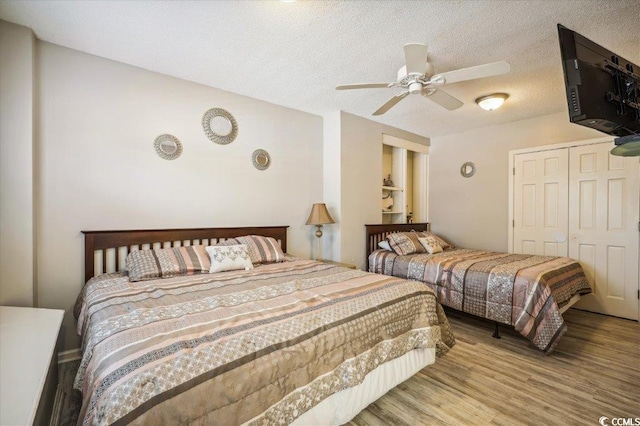 bedroom featuring wood finished floors, a closet, ceiling fan, and a textured ceiling
