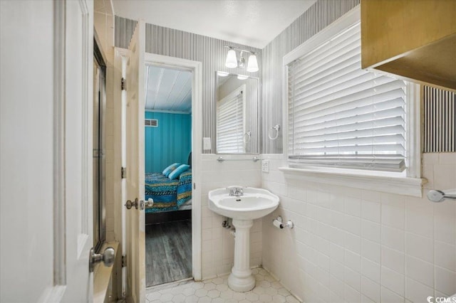 ensuite bathroom with tile walls and tile patterned floors