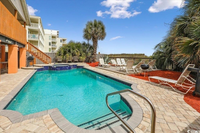 view of swimming pool with stairs, a pool with connected hot tub, a patio, and fence
