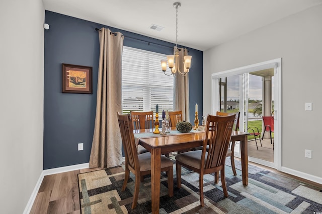 dining space featuring a chandelier, baseboards, and wood finished floors