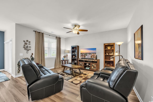 living area featuring a ceiling fan, light wood-style floors, and baseboards