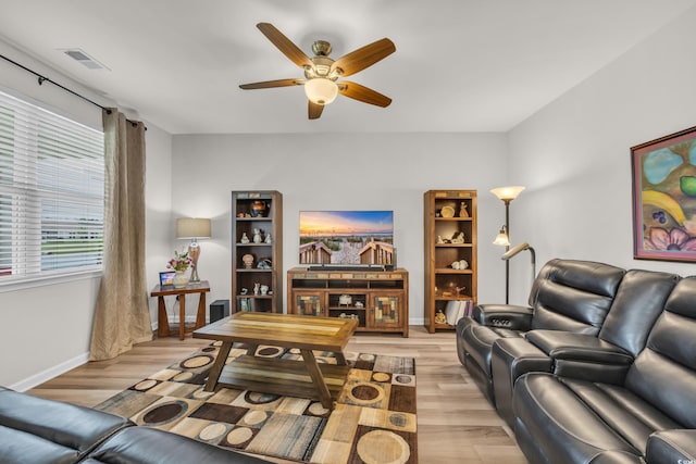 living room with a ceiling fan, light wood finished floors, and baseboards
