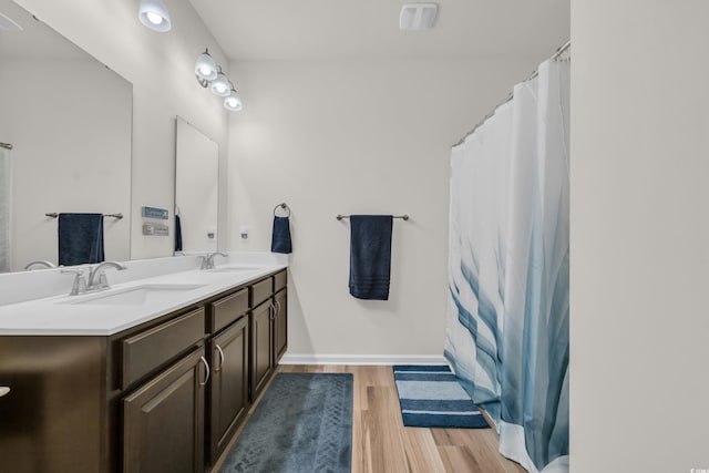 bathroom with wood finished floors, double vanity, and a shower with curtain