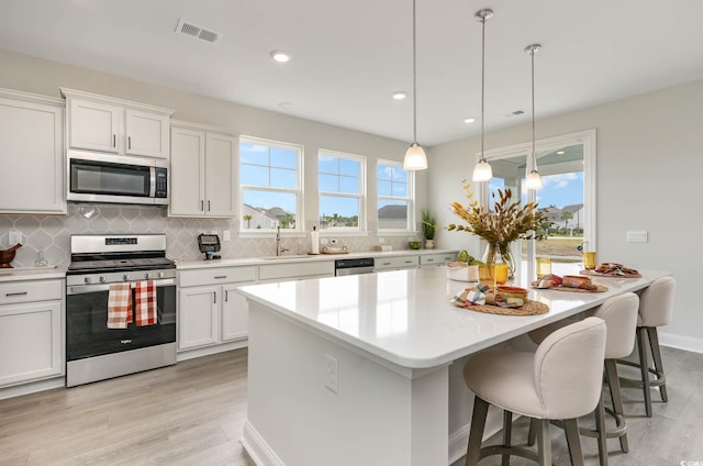 814 Belle Dr, North Myrtle Beach, SC 29582 - kitchen featuring appliances with stainless steel finishes, a sink, tasteful backsplash, a center island, and light wood-style flooring
