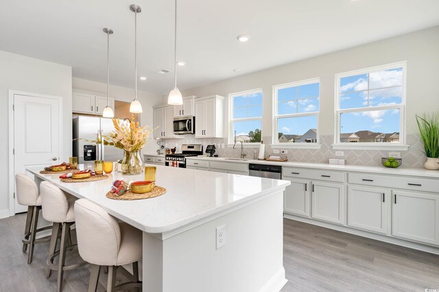 814 Belle Dr, North Myrtle Beach, SC 29582 - kitchen with appliances with stainless steel finishes, a sink, a breakfast bar area, light wood-style floors, and a kitchen island
