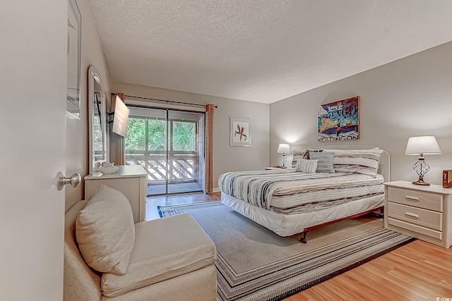 bedroom featuring access to exterior, light wood-type flooring, and a textured ceiling