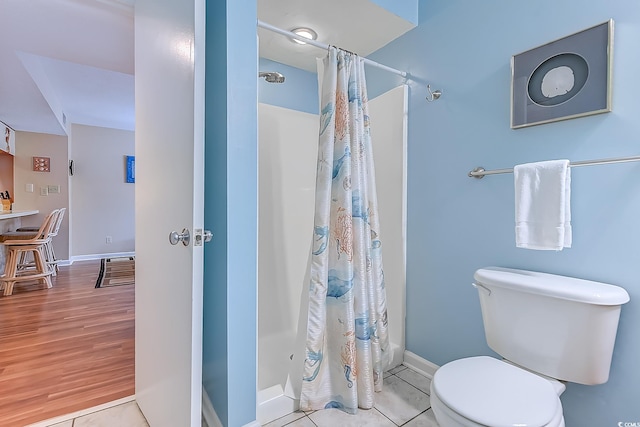 full bath with a stall shower, toilet, baseboards, and wood finished floors
