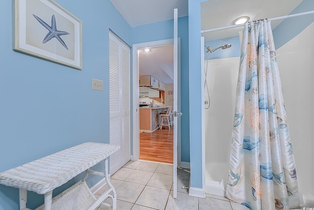 bathroom with a shower with shower curtain, tile patterned flooring, and baseboards