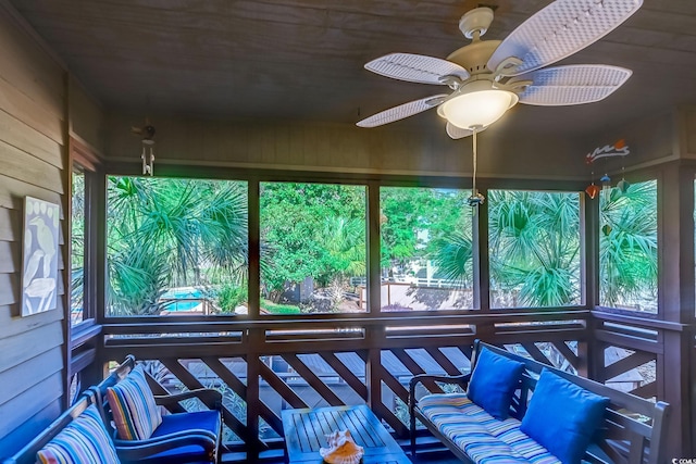 sunroom / solarium with healthy amount of natural light, ceiling fan, wooden walls, and wooden ceiling