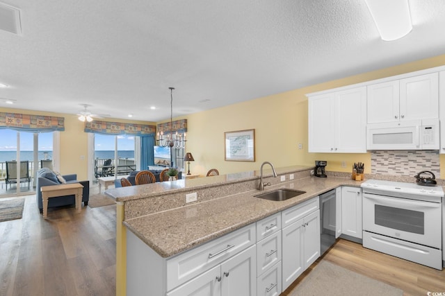 17 N Seaside Dr, Surfside Beach, SC 29575 - kitchen featuring white appliances, a sink, a peninsula, light wood-style flooring, and white cabinets