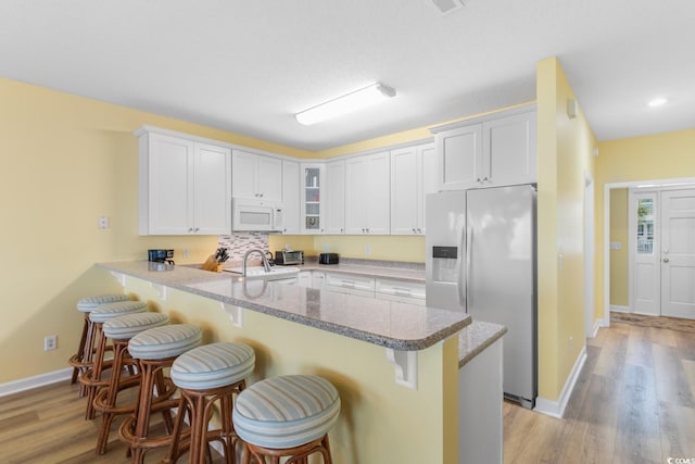17 N Seaside Dr, Surfside Beach, SC 29575 - kitchen featuring white appliances, a peninsula, a breakfast bar area, glass insert cabinets, and recessed lighting