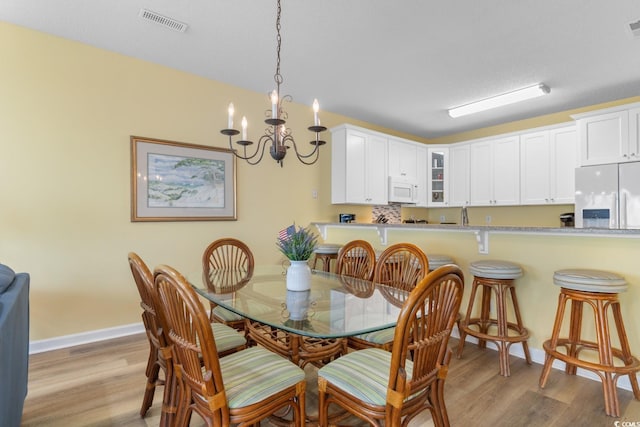 17 N Seaside Dr, Surfside Beach, SC 29575 - dining area featuring light wood-style floors, a chandelier, and baseboards