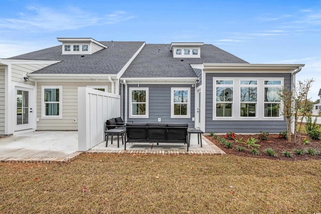 rear view of property featuring a shingled roof, a lawn, and a patio area