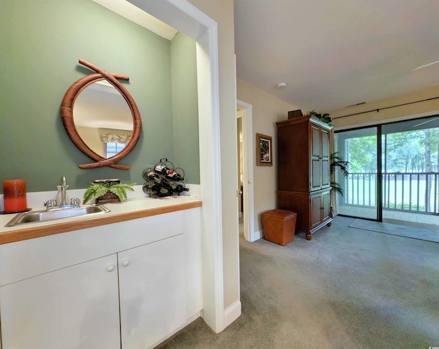 hallway featuring a sink, light colored carpet, and baseboards