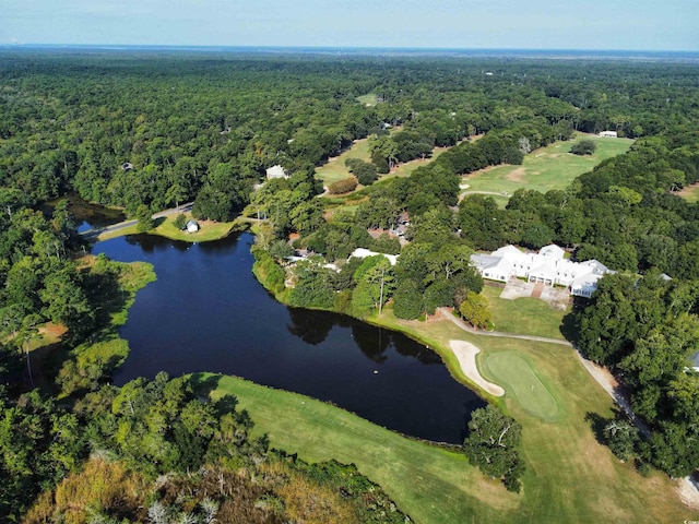 view of property location featuring a heavily wooded area, a nearby body of water, and a local golf course