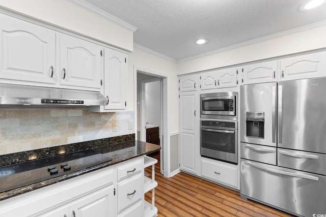 8207 Timber Ridge Rd, Conway, SC 29526 - kitchen featuring appliances with stainless steel finishes, under cabinet range hood, ornamental molding, dark stone counters, and white cabinets