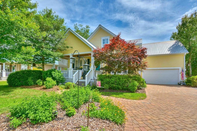 view of property hidden behind natural elements with covered porch, decorative driveway, and metal roof