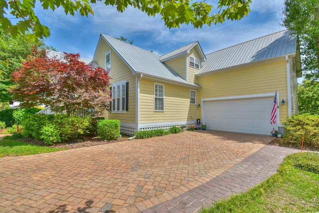 view of front facade with decorative driveway, metal roof, and a garage