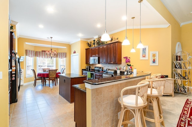 4608 Grovecrest Cir N, Myrtle Beach, SC 29582 - kitchen with stainless steel appliances, a kitchen island, crown molding, light tile patterned floors, and a chandelier