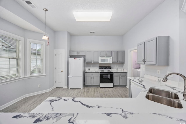 9831 Winchester Ct, Murrells Inlet, SC 29576 - kitchen with white appliances, gray cabinets, washer and dryer, light wood-type flooring, and pendant lighting