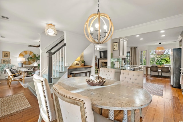2170 Deerfield Ave, Surfside Beach, SC 29575 - dining space with a chandelier, crown molding, stairway, light wood-type flooring, and ceiling fan