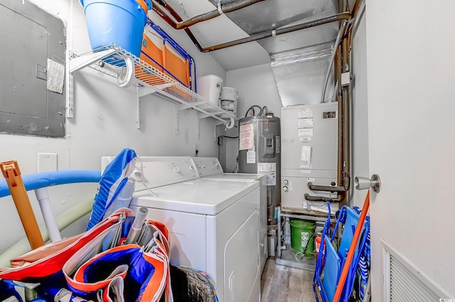 washroom with electric panel, separate washer and dryer, wood finished floors, and electric water heater
