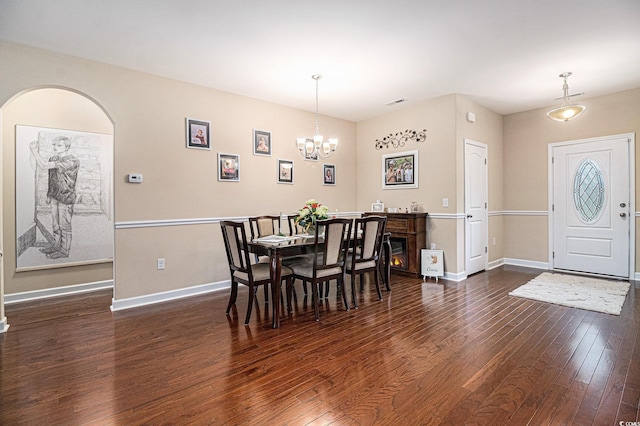 dining space featuring a chandelier, dark wood-type flooring, and baseboards