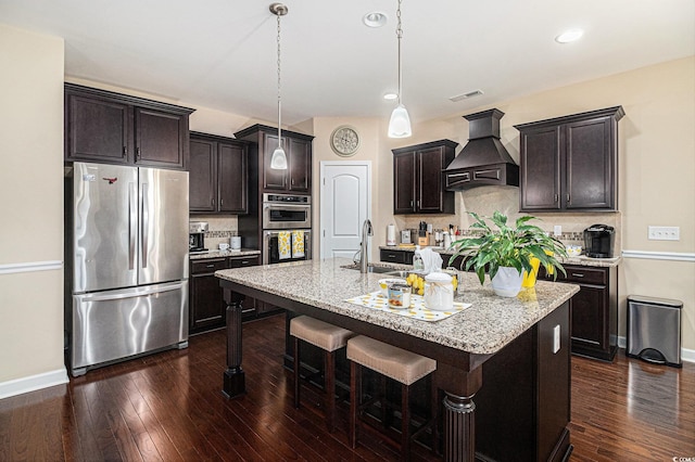 kitchen featuring stainless steel appliances, custom range hood, a sink, baseboards, and recessed lighting