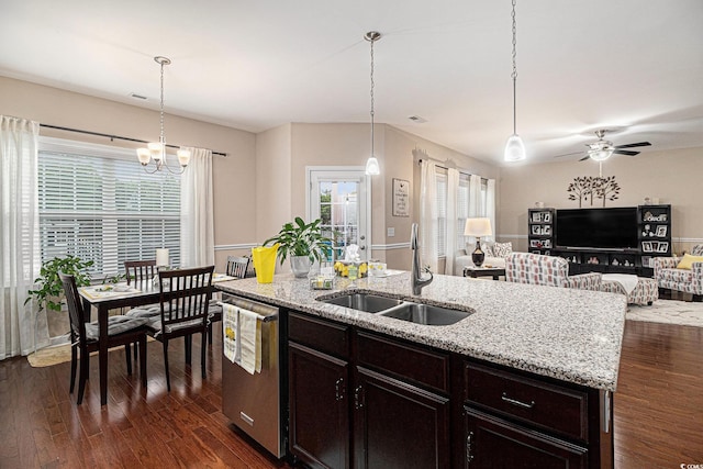 kitchen with a sink, stainless steel dishwasher, dark wood-type flooring, a ceiling fan, and light stone counters