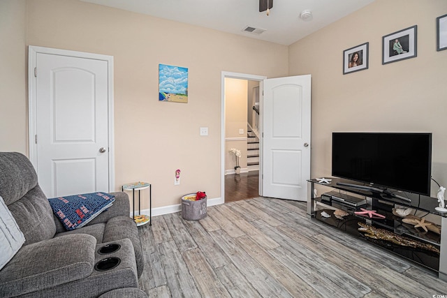 living room featuring wood finished floors, ceiling fan, stairs, and baseboards