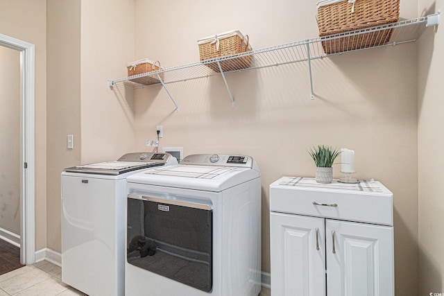 laundry room featuring washing machine and dryer, baseboards, cabinet space, and light tile patterned floors